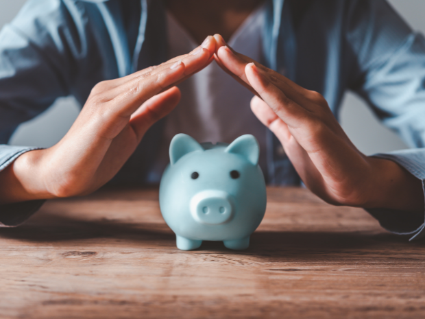 Photo of a person protecting their piggy bank